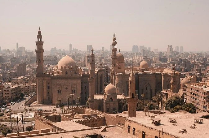 Una vista nebbiosa sulle cupole e i minareti del Cairo islamico con Sultan Hassan in primo piano