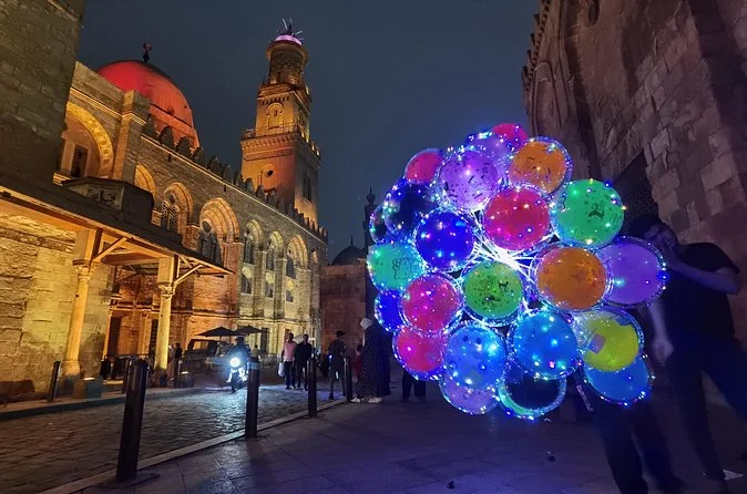 Die Al-Muizz-Straße bei Nacht mit beleuchteten Fassaden und Spaziergängern